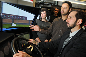 From left: Lisa Rinaldi, engineering students Ahmed Migdadi and Ranvir Dhillon, and Jason Rinaldi in the new Frank Rinaldi Truck Driving Simulator Laboratory.