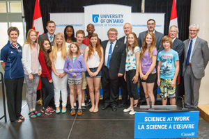 Grade 7 and 8 students from Sherwood Public School in Oshawa, Ontario are joined by (from left): Janet Walden, Chief Operating Officer, Natural Sciences and Engineering Research Council of Canada; Dr. Christopher Collins, UOIT Canada Research Chair in Linguistic Information Visualization; Ed Holder, Minister of State (Science and Technology); Dr. Colin Carrie, Member of Parliament for Oshawa; Dr. Qusay Mahmoud, Professor, Faculty of Engineering and Applied Science and Chair, Department of Electrical, Computer and Software Engineering, UOIT; Dr. Michael Owen, Vice-President, Research, Innovation and International, UOIT; and President and Vice-Chancellor Tim McTiernan, PhD, UOIT.