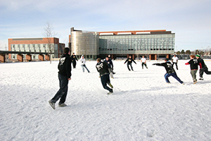 Students playing football in front of UOIT Campus Library in the winter - thumbnail