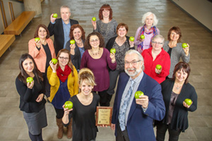 Stacey Papanicolaou of the Durham Region Health Department (front left) presents the Healthy Workplace Award to Murray Lapp, Vice-President, Human Resources and Services, UOIT (front right). Behind: Committee members hold green apples (HWC symbol).