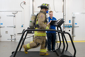 Michael Williams-Bell (right), PhD candidate (Applied Bioscience) conducts heat exertion test with a City of Toronto firefighter in one of ACE's climate chambers (temperature approximately 35 Celsius).