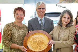 From left: Glenna Raymond, Chair, UOIT Board of Governors and Tim McTiernan, PhD, UOIT President with Noreen Taylor, President, Windfields Farm Limited, who received a platter, carved from a barn door that once graced the property, at a special celebration held on June 23.