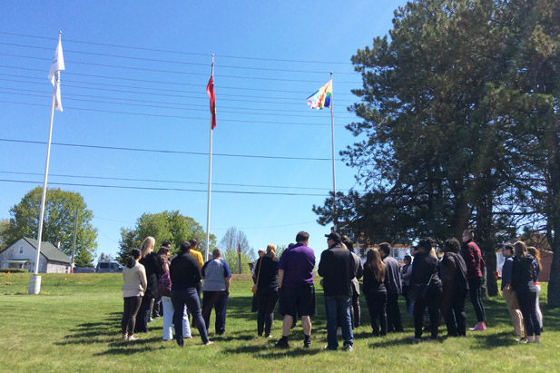 Students, faculty and staff gathered in front of the flag poles at the north campus location, where they were joined by representatives from community partners including PFLAG Durham and the AIDS Committee of Durham Region.