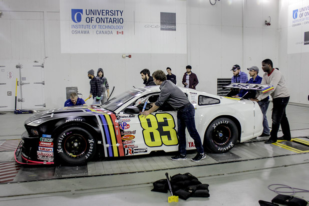 During a practical aerodynamic workshop, students position a race car in front of the nozzle of the ACE Climatic Wind Tunnel.