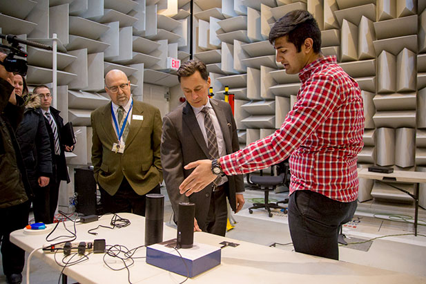 The Honourable Brad Duguid, Minister of Economic Development and Growth (second from right) chats with Sheraz Tariq, Researcher, Unified Computer Intelligence Corporation (right) about testing the performance of far field voice interactive technologies inside ACE's hemi-anechoic (low vibration) chamber. Observing is John Komar, Director, Engineering and Operations, ACE (March 15, 2017). 