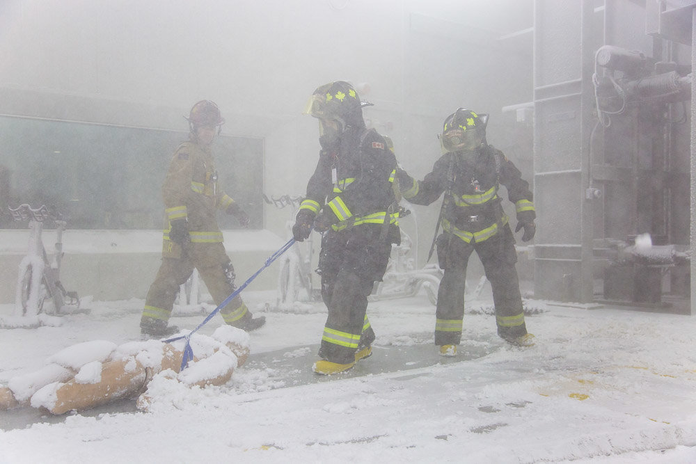 Firefighter students drag a mannequin through extreme cold conditions.
