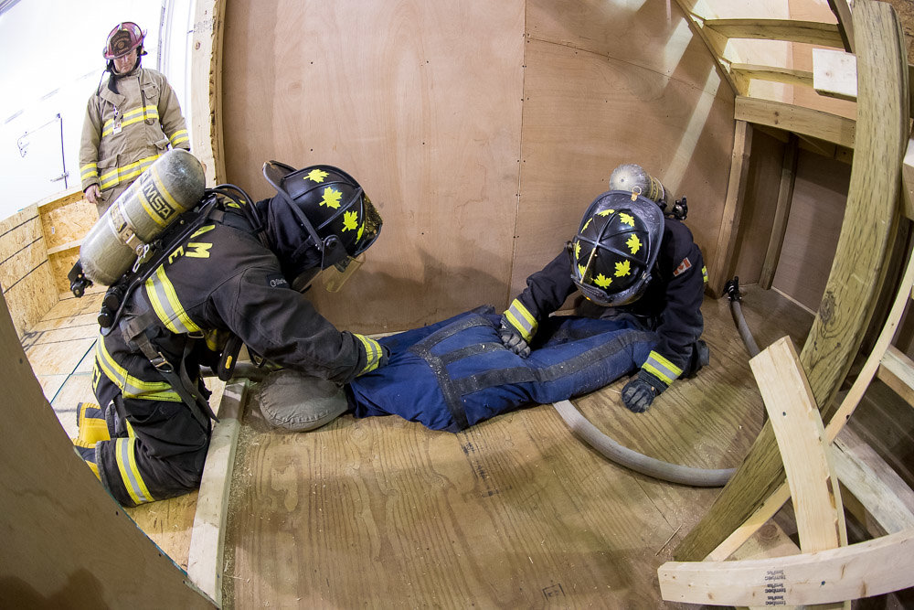 Firefighter students drag a 57-kilogram (125-pound) mannequin through the heat maze to safety.