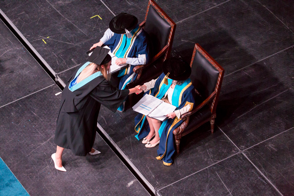 Graduates crossing the stage to greet President and Vice-Chancellor Tim McTiernan and Chancellor Noreen Taylor.