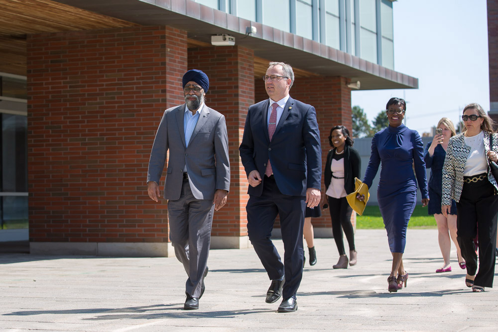 Minister Harjit Singh Sajjan and President Steven Murphy walk toward ACE with the rest of the tour group.