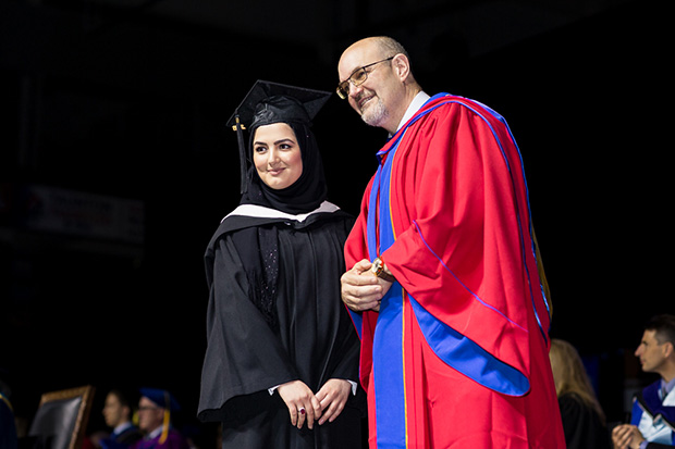 Political Science graduate Sadaf Parweez (left), accepts congratulations from Peter Stoett, PhD, Dean, Faculty of Social Science and Humanities at the university's 2018 Convocation ceremony (June 8, 2018).