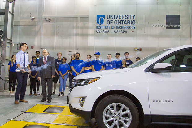 Prime Minister Justin Trudeau uses a smoke wand to demonstrate how engineers detect wind flow over vehicles in front of the nozzle of the Climatic Wind Tunnel at the University of Ontario Institute of Technology (with students from the Faculty of Engineering and Applied Science; August 31, 2018).