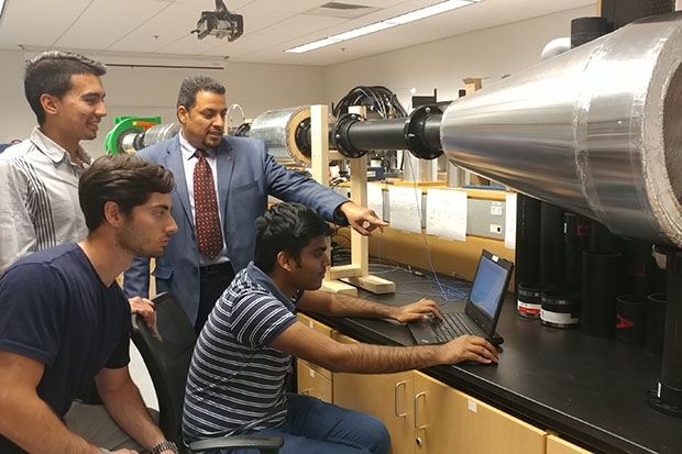 Master of Science in Mechanical Engineering students Thomas Lato (standing), Karim Sachedina (seated) and Mdrashidul Islam (using the computer) worked with Atef Mohany, PhD, Associate Professor, Faculty of Engineering and Applied Science, to create a prototype for a new vent silencer design for Stoddard Silencers.