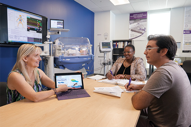 Dr. Carolyn McGregor (left) consults with members of her research team (Computer Science PhD candidate Catherine Inibhunu and 2018 Computer Science PhD graduate Roozbeh Jalali) in the Health Informatics Research Laboratory at the University of Ontario Institute of Technology.