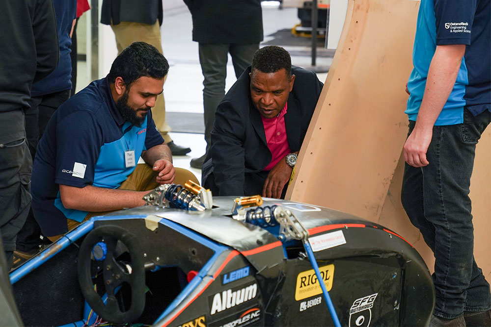 Francis Garwe, Member of Ontario Tech University's Board of Governors (centre) meets with the Ontario Tech Racing team.