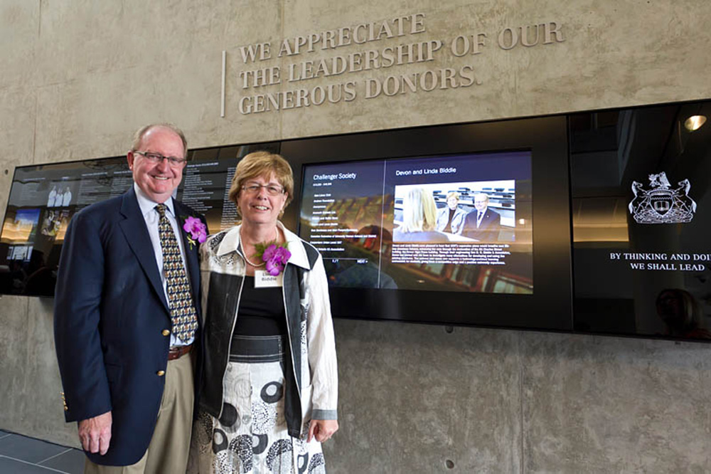 File image of Devon Biddle (left) with Linda Biddle at the donor wall in the Atrium of Ontario Tech University's Energy Systems and Nuclear Science Research Centre.