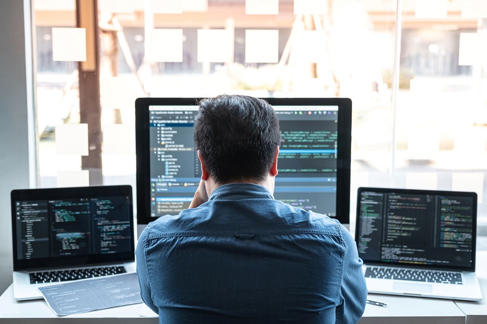 Person in front of three computer screens