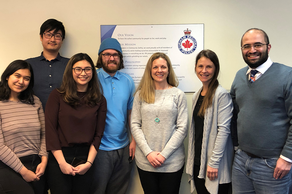 (Please note: image from February 2020, prior to physical distancing and mask protocols), From left: Ontario Tech University Faculty of Business and Information Technology (FBIT) students Atiya Nova, Wen Bo Yu, Angela Tabafunda and Chris Bull; Holly Britton, Health, Wellness and Safety Manager. Durham Regional Police Service (DRPS); Dr. Krystle Martin, Ontario Shores Research Scientist and DRPS Consultant; and Dr. Pejman Mirza-Babaei, Associate Professor, FBIT, Ontario Tech University.  