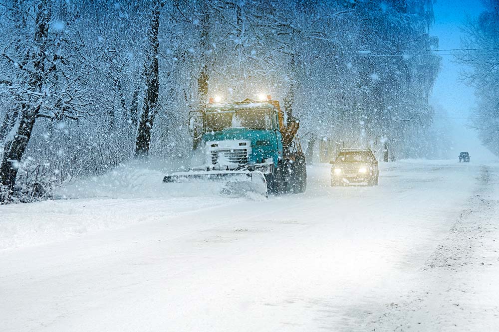 image of snow plow clearing road during a winter storm