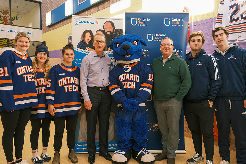 Members of the Ontario Tech Ridgebacks women's and men's hockey teams and Hunter the Ridgeback, with Tom McHugh, CEO, Grandview Kids (fourth from left), and Dr. Steven Murphy, President and Vice-Chancellor, Ontario Tech University (third from right).
