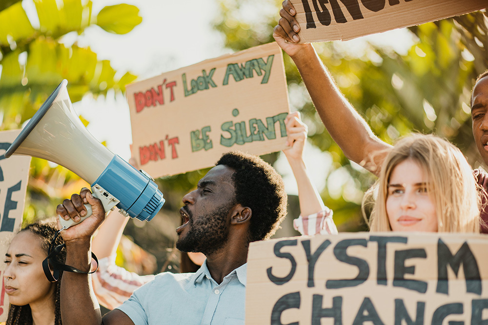 People hold a megaphone and signs at a protest.