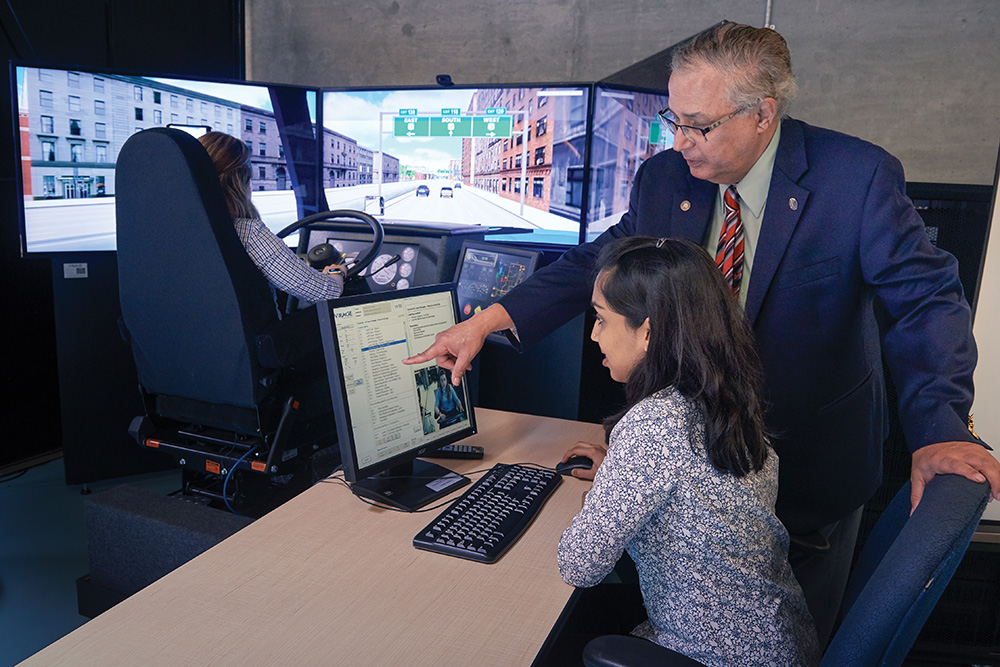 Dr. Moustafa El-Gindy, Professor, Faculty of Engineering and Applied Science speaks with student in the Truck Driving Simulator Laboratory that explores heavy vehicle dynamics.