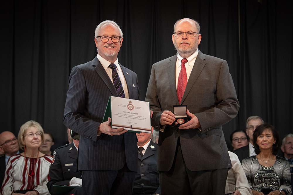William Thurber, Associate Teaching Professor, Faculty of Business and Information Technology, Ontario Tech University (right) receives Queen Elizabeth II Platinum Jubilee Award from Colin Carrie, Member of Parliament for Oshawa (December 16, 2022).