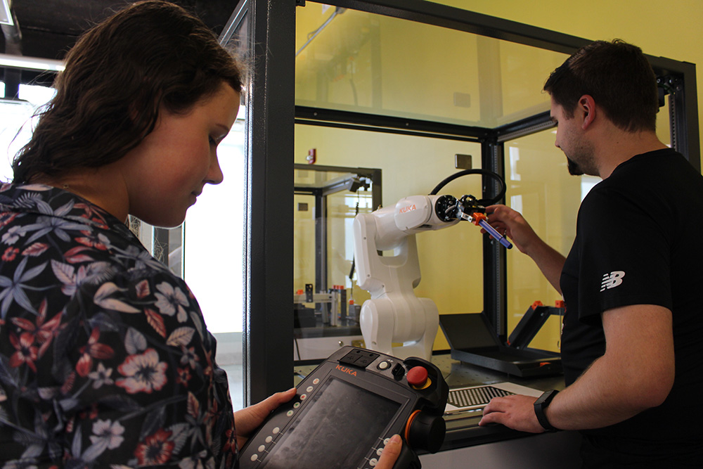 Ontario Tech University Master of Applied Science (Mechanical Engineering) students Noor Khabbaz (left) and Cameron Slade use one of the new robot work cells in the Faculty of Engineering and Applied Science's Robotics and Automation Laboratory.