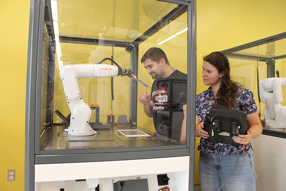 Ontario Tech University Master of Applied Science (Mechanical Engineering) students Cameron Slade (left) and Noor Khabbaz use one of the new robot work cells in the Faculty of Engineering and Applied Science's Robotics and Automation Laboratory (October 4, 2023).