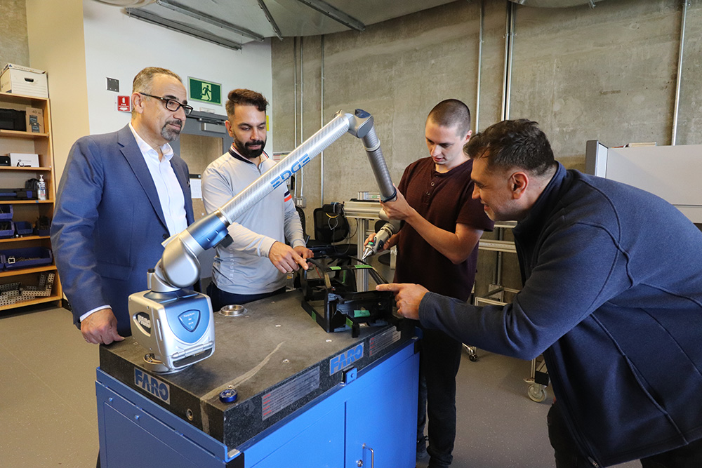 Dr. Hossam Kishawy, Dean and Professor, Faculty of Engineering and Applied Science (FEAS), Dr. Mohsen Tayefeh, FEAS Research Associate and Industrial Engineering Supervisor at Ontario Tech, Dylan Bender, FEAS PhD candidate, and Dr. Ahmad Barari, Professor, FEAS, using a precise measuring tool on a prototype.  