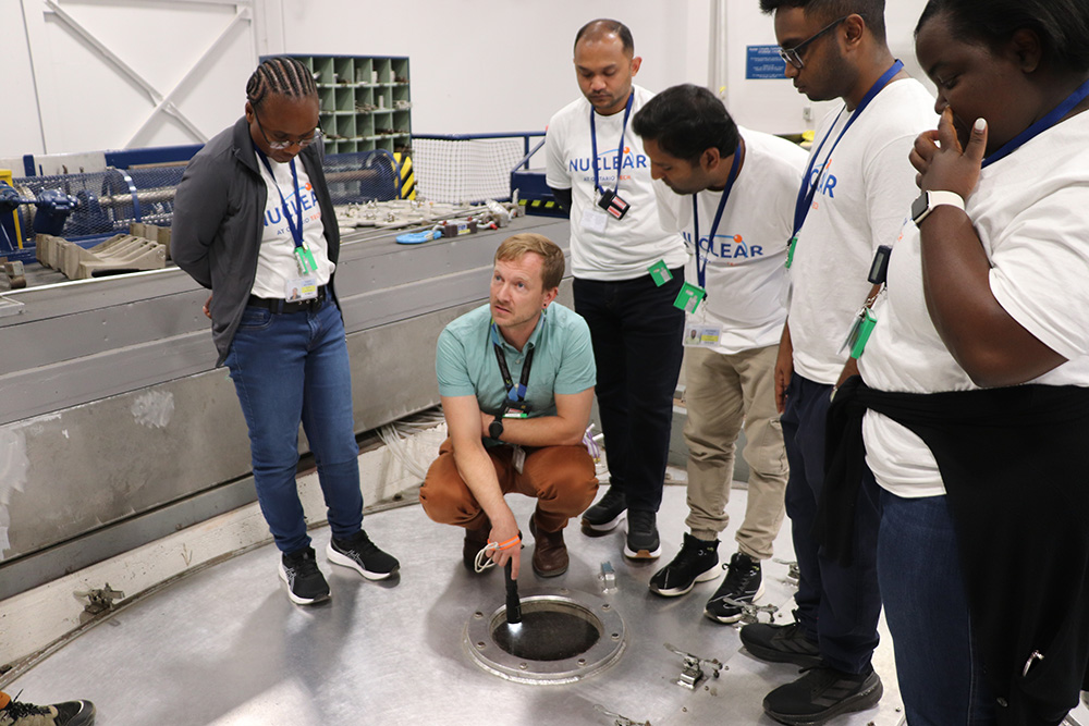 Ontario Tech University graduate students observe CNL reactor physicist Julian Atfield pointing a flashlight down into the ZED-2 reactor’s core during a tour of CNL’s Chalk River, Ontario facility, during CNL’s 2025 Immersive Experience Week program. (August 2025)  