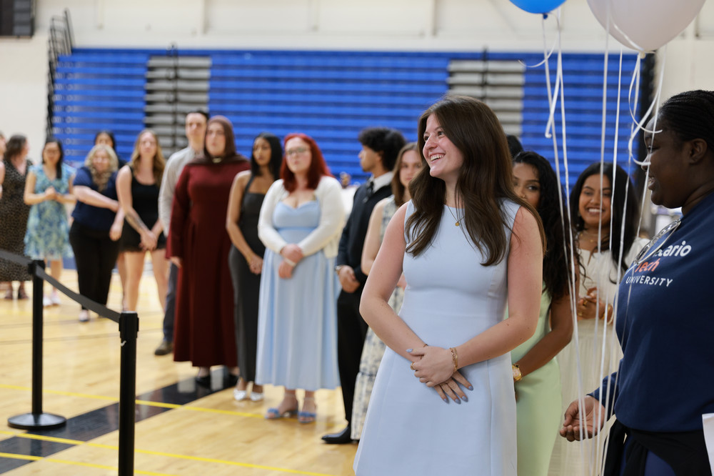 Student smiling, standing in line during ceremony 