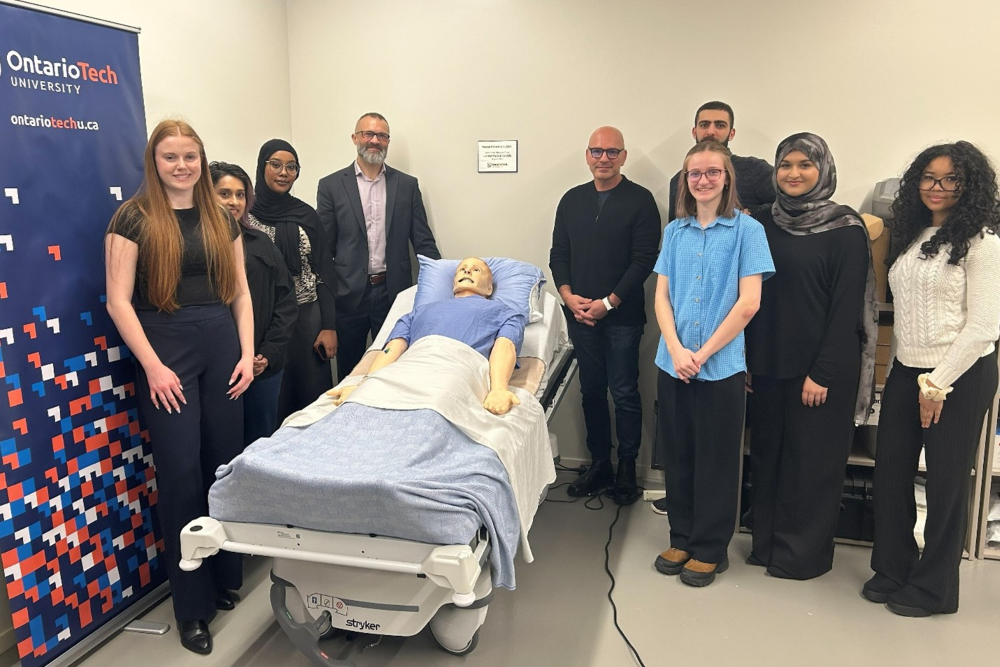 Dr. Adam Dubrowski, Canada Research Chair in Health-Care Simulation and Professor in Ontario Tech’s Faculty of Health Sciences (FHSc) (centre left), and Bruce Karatzoglou, Manager of Educational and Technical Services, Laerdal Medical Canada (centre right), with FHSc students alongside the donated high-fidelity simulation mannequin.