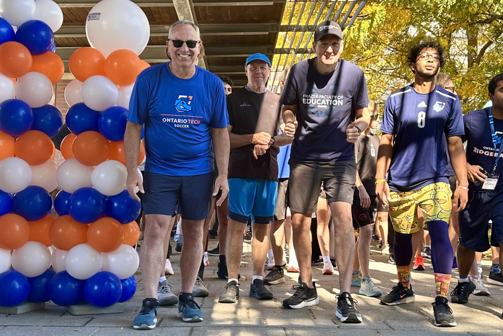 Ontario Tech University President Steven Murphy (centre-left, royal blue T-shirt) and Chancellor Mitch Frazer (centre-right, navy T-shirt) lead participants at the 2026 Ontario Tech Chancellor's Challenge, part of the Community Day activities on October 3, 2026.